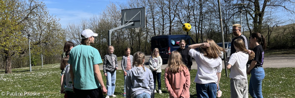 Gruppe steht im Kreis und wirft einen Ball